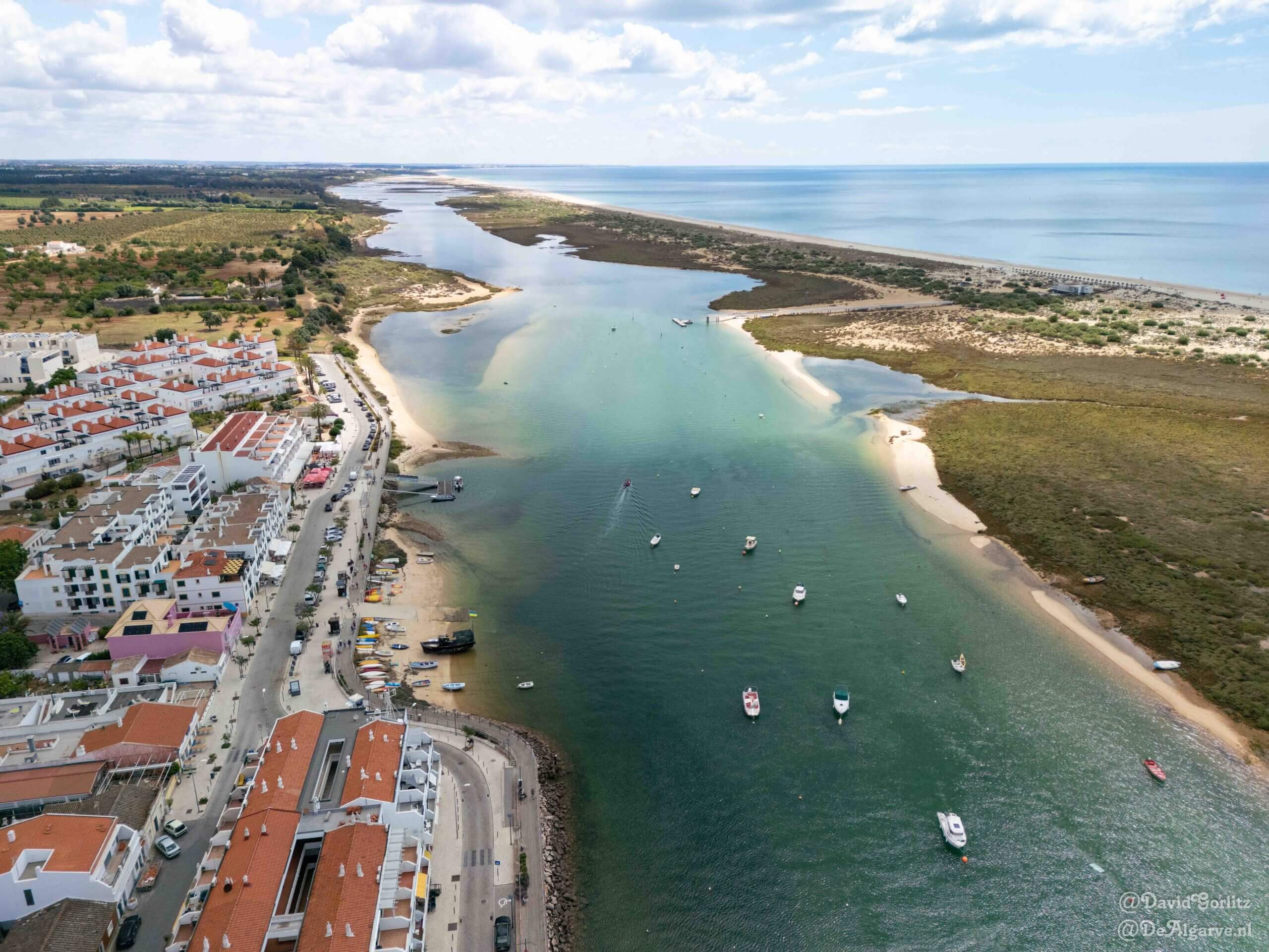 Beautiful sunlit view of the traditional fishing boats and wooden boardwalks running along the scenic waterfront of Cabanas de Tavira