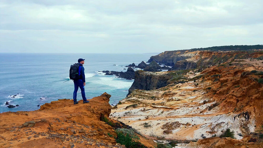 Coastal hikers trekking along a panoramic clifftop trail overlooking the ocean in southwest Portugal
